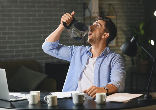 Man drinking coffee from a pot at a desk, exploring caffeine intake for energy without side effects.