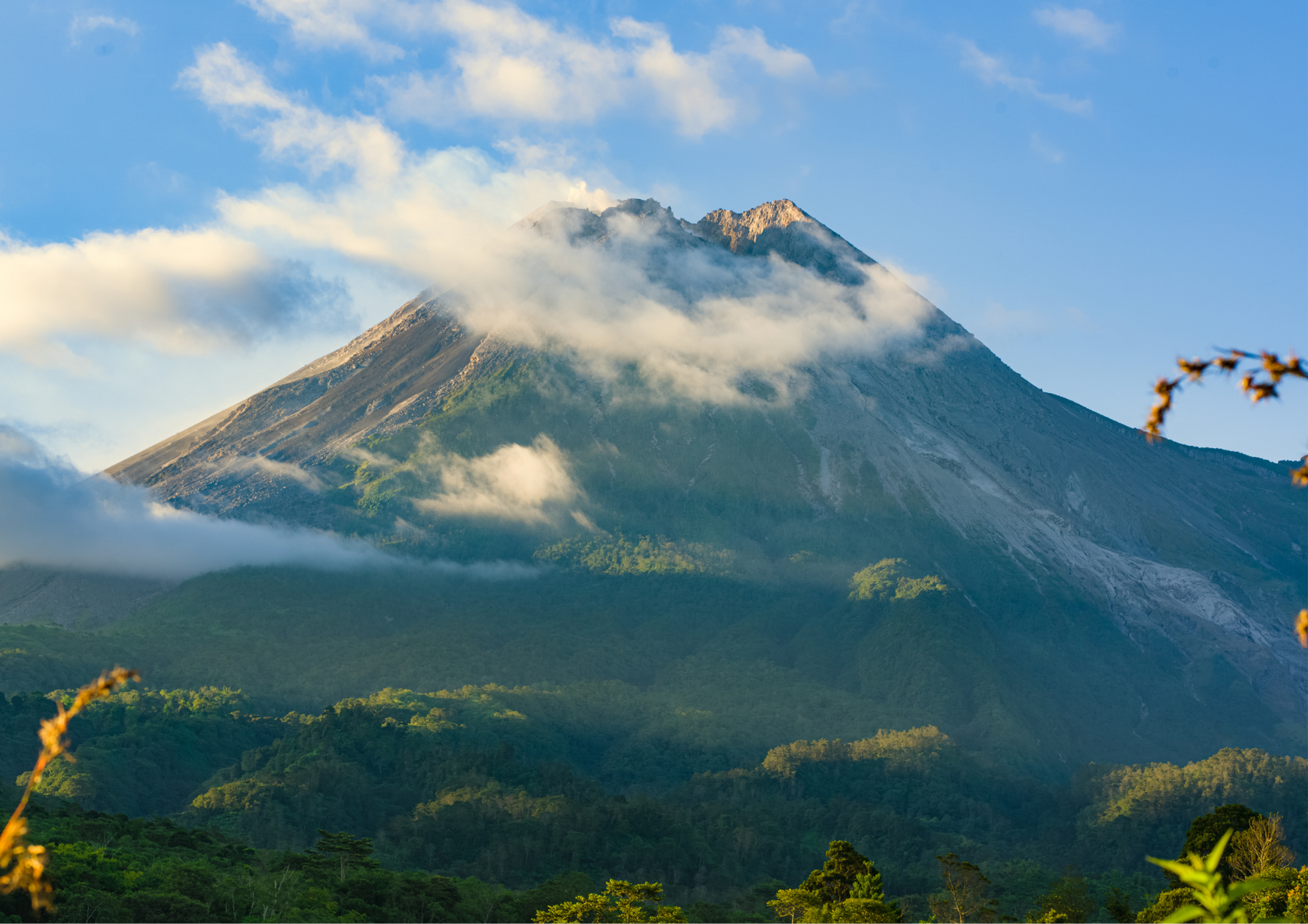 Mountain with clouds and lush greenery under a blue sky in Kenya, highlighting the scenic highlands where Kirenge Gold premium Kenyan coffee is cultivated.
