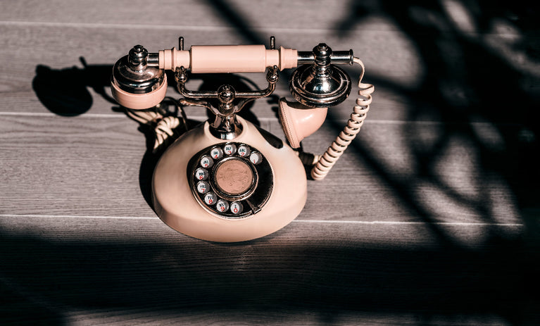 Vintage old-fashioned telephone on a desk, representing classic communication, with subtle Kirenge Gold coffee branding in the background.